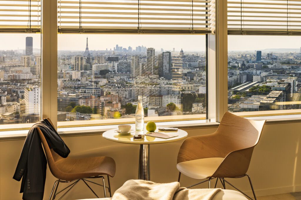 Vue panoramique sur Paris depuis une suite du TOO Hotel, avec la Tour Eiffel en arrière-plan. Un cadre élégant et lumineux avec un petit-déjeuner en chambre.