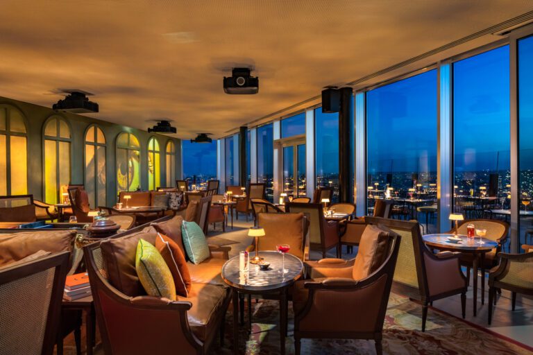 Vue intérieure du TOO TacTac Skybar à Paris, avec ambiance chic, canapés confortables et vue panoramique sur la ville illuminée.